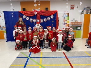 Grupa dzieci w strojach świątecznych z nauczycielami i Mikołajem