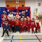 Grupa dzieci i dorosłych w mikołajkach i czapkach świątecznych