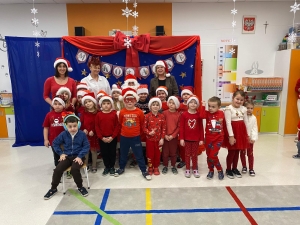 Grupa dzieci i dorosłych w mikołajkach i czapkach świątecznych