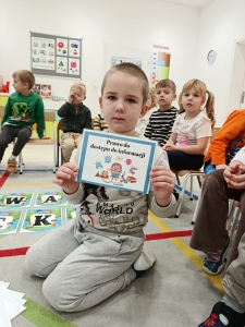 Dziecko trzyma kartkę z napisem "Prawo do dostępu do informacji"
