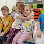 Dwie dziewczynki obejmują się w przedszkolu. Wokół inne dzieci