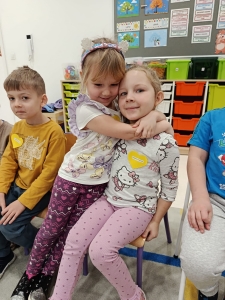 Dwie dziewczynki obejmują się w przedszkolu. Wokół inne dzieci