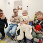 Czterech chłopców siedzi na krzesłach, trzymając pluszaki