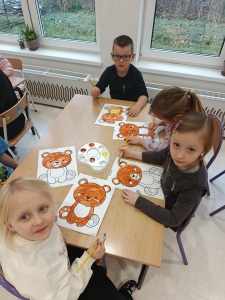 Dzieci malują niedźwiadki na arkuszach papieru w klasie