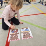 Dziewczynka siedzi na podłodze i układa kartonki z wizerunkami