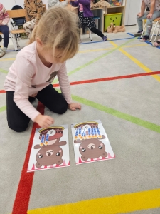 Dziewczynka siedzi na podłodze i układa kartonki z wizerunkami