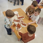 Dzieci przygotowują pizzę na stole w przedszkolu