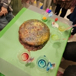 Duży ciasto na zielonym stole z różnymi kolorowymi płynami