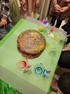 Duży ciasto na zielonym stole z różnymi kolorowymi płynami