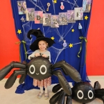 Dziewczynka w czarnym kapeluszu trzyma balon w kształcie pająka