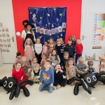 Grupa dzieci i nauczycielki w przebraniach na tle dekoracji