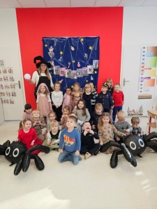 Grupa dzieci i nauczycielki w przebraniach na tle dekoracji