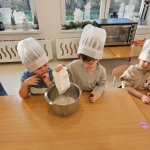 Dzieci w czapkach kuchennych mieszają składniki w misce