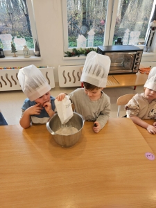 Dzieci w czapkach kuchennych mieszają składniki w misce