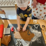 Dziecko w czapce kuchennej formuje ciasteczka z ciasta