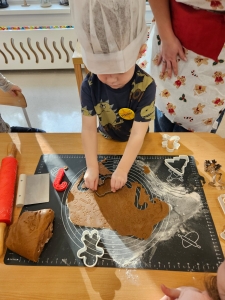 Dziecko w czapce kuchennej formuje ciasteczka z ciasta