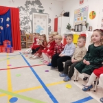 Dzieci siedzą w szkolnym pomieszczeniu na krzesłach
