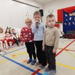 Trzech chłopców stoi na scenie, jeden trzyma mikrofon