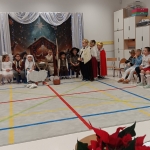 Dzieci w kostiumach występują na scenie w szkolnej sali. (45 znaków)