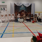 Dzieci w strojach przed sceną z żłóbkiem w tle