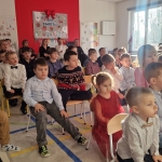 Grupa dzieci siedzi na krzesłach w sali lekcyjnej