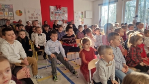 Grupa dzieci siedzi na krzesłach w sali lekcyjnej