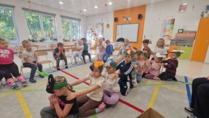Grupa dzieci w przedszkolu siedzi na podłodze w sali lekcyjnej