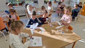 Dzieci w przedszkolu robią wycinanki przy stolach