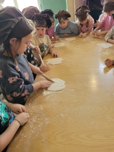 Dzieci w czapkach kuchennych robią ciasto na stole