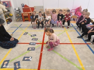 Dzieci w przedszkolu grają w grę na podłodze z kartami