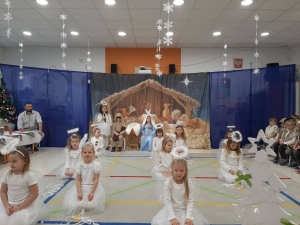 Dzieci w strojach aniołów przed żłóbkiem w szkole