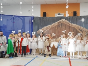 Dzieci w strojach przedstawiają scenę Bożego Narodzenia na scenie