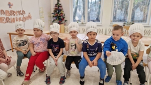 Grupa dzieci w czapkach kuchennych siedzi na podłodze